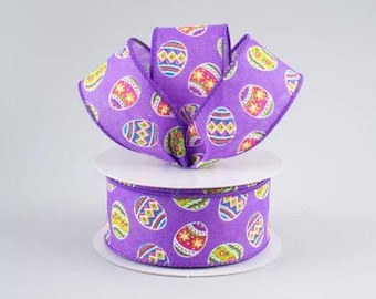 May include: A roll of purple ribbon featuring a repeating pattern of colourful Easter eggs. The ribbon is fashioned into a decorative bow, highlighting the egg design. The ribbon is on a white spool.