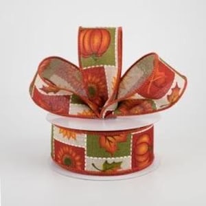 May include: A roll of 2.5 inch wide fabric ribbon with a patchwork design featuring pumpkins, sunflowers, and leaves in shades of orange, green, and brown. The ribbon has a textured, linen-like finish.