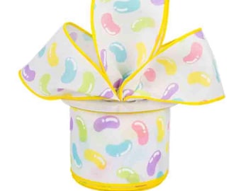 May include: A white ribbon with a yellow border and a jelly bean pattern. The ribbon is tied into a bow shape.