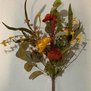 May include: A vibrant bouquet of artificial flowers featuring orange, yellow, and red blooms. The arrangement includes various green leaves and stems, creating a natural and colorful display. Perfect for home decor or crafting.