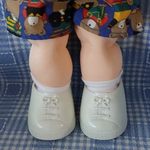 K&ouml;nnte beinhalten: Ein Paar wei&szlig;e Sneaker mit wei&szlig;en Schn&uuml;rsenkeln und einem hellblauen und wei&szlig;en karierten Hintergrund.