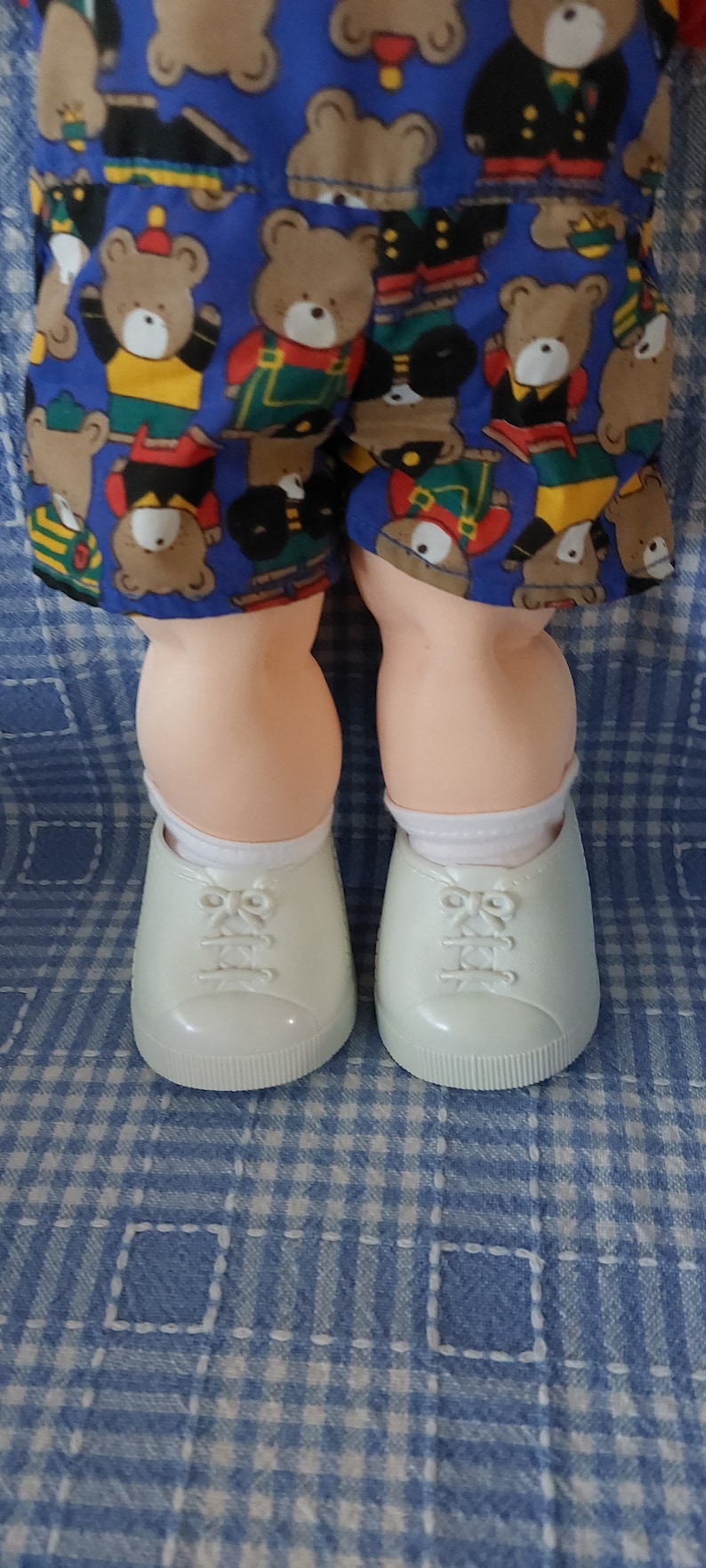 K&ouml;nnte beinhalten: Ein Paar wei&szlig;e Sneaker mit wei&szlig;en Schn&uuml;rsenkeln und einem hellblauen und wei&szlig;en karierten Hintergrund.