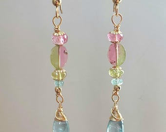 May include: A pair of gold dangle earrings with pink, green, and blue gemstones. The earrings are made with wire wrapped gemstones.