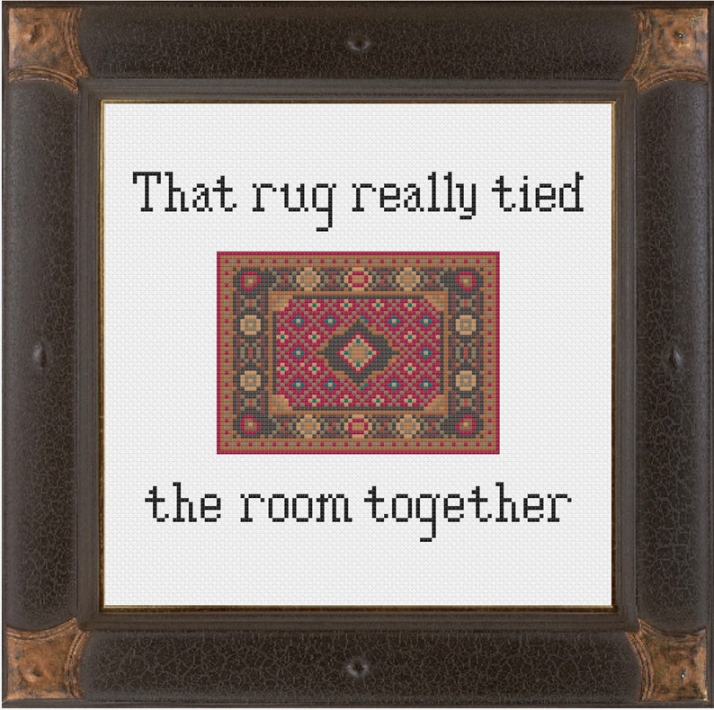 May include: A white framed cross-stitch with a red, black, and gold patterned rug and the text "That rug really tied the room together."