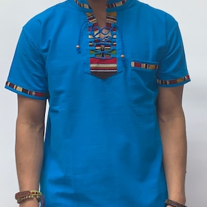 May include: A blue short-sleeved shirt with a lace-up neckline and colorful trim. The shirt has a small pocket on the right side.