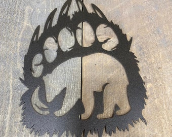 May include: Black metal bear paw print silhouette with a bear outline inside. The paw print has a textured finish.