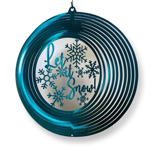 Pode incluir: Um moinho de vento de metal turquesa com as palavras "Let it Snow!" e flocos de neve recortados.