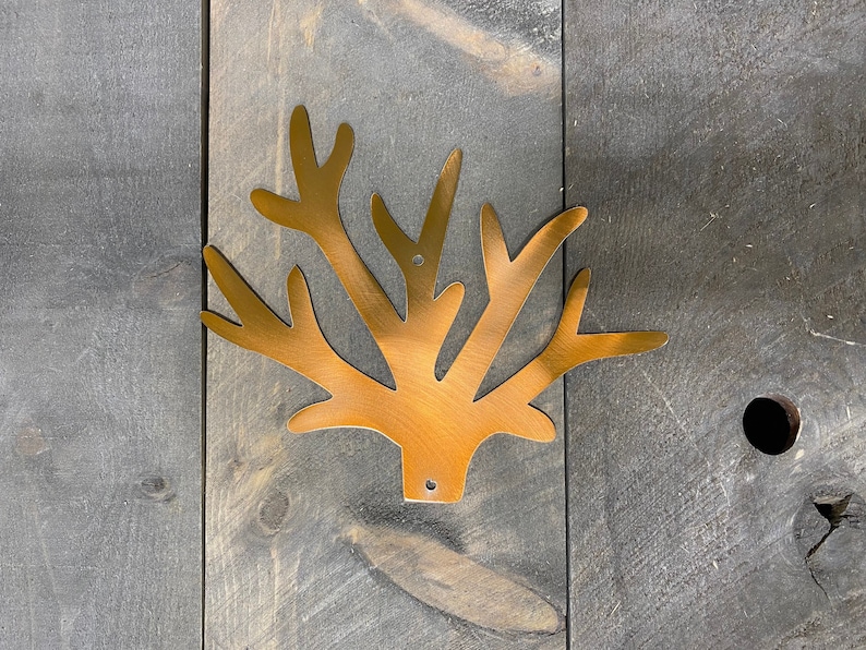 Puede incluir: Una decoraci&oacute;n de pared de metal dorado en forma de rama de &aacute;rbol estilizada con m&uacute;ltiples ramas.