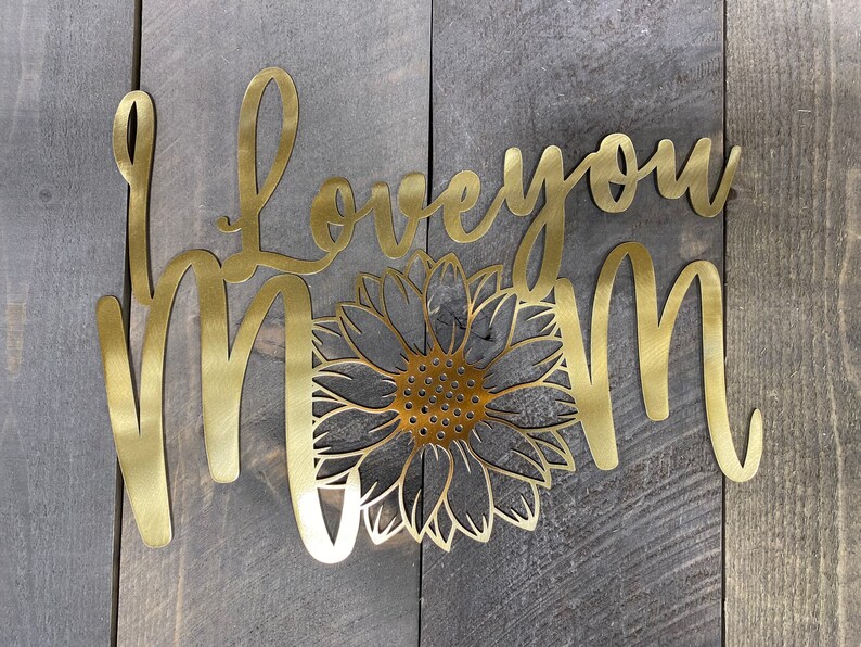 May include: Gold metal wall art with the words "Love you Mom" and a sunflower design.