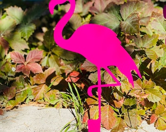 May include: A bright pink metal flamingo lawn ornament. The flamingo is standing on one leg with its head bent down. The ornament is made of metal and has a shiny finish.