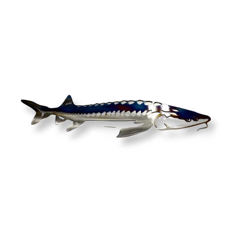 May include: A metal sculpture of a sturgeon fish with a blue and silver finish. The sturgeon has a long, slender body with a pointed snout and a dorsal fin.