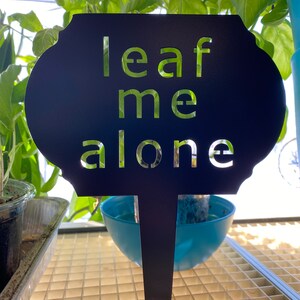 May include: Black metal garden stake with the words "leaf me alone" cut out in a white font.