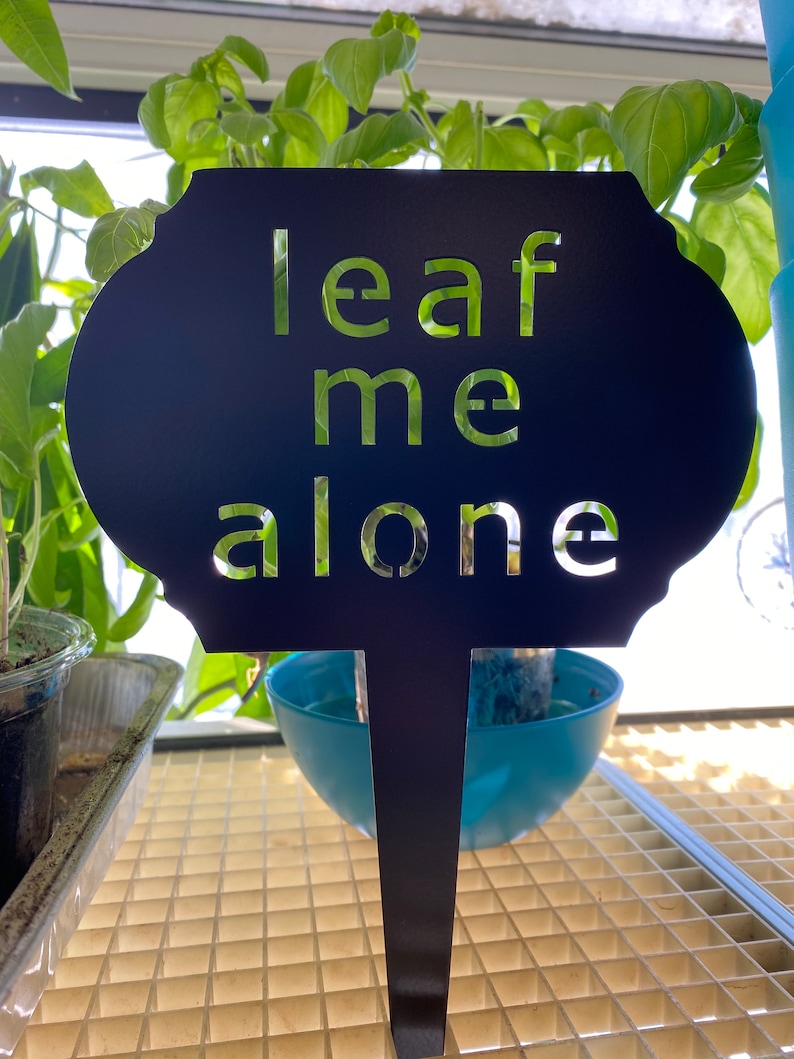May include: Black metal garden stake with the words "leaf me alone" cut out in a white font.