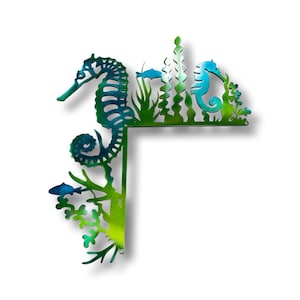 May include: A metal wall art piece featuring two seahorses and seaweed in shades of green and blue. The seahorses are facing each other and are surrounded by seaweed. The piece is designed to be placed in a corner.