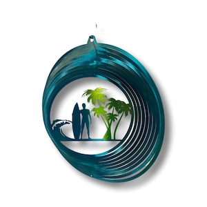 May include: A teal blue metal wind spinner with a surfer silhouette and palm trees in the center. The wind spinner has multiple layers of metal that spin in the wind.