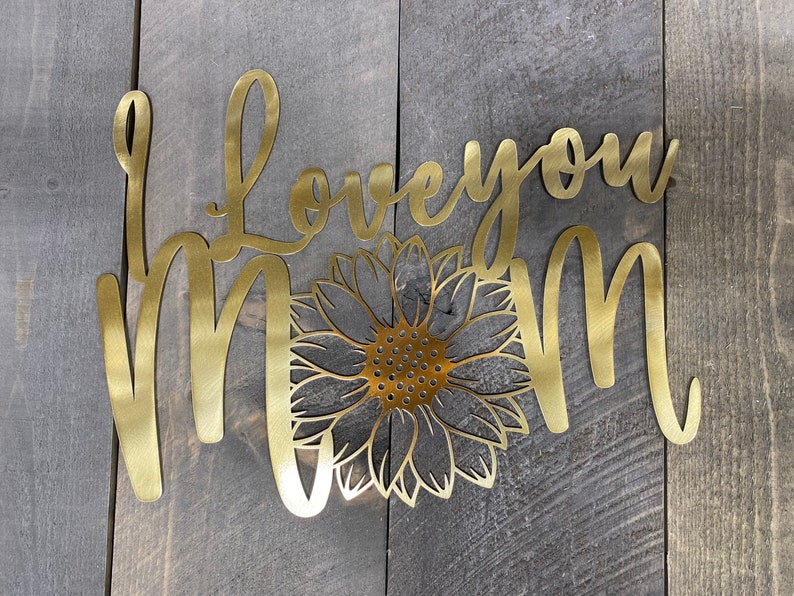 May include: Gold metal wall decor with the words "I love you Mom" and a sunflower design.