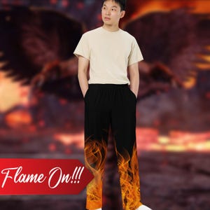 Può includere: Pantaloni neri con un designo a fiamma sulle gambe. I pantaloni hanno una cintura elastica e sono realizzati in un tessuto morbido e confortevole. "Flame On!!!" è scritto in rosso su sfondo bianco.