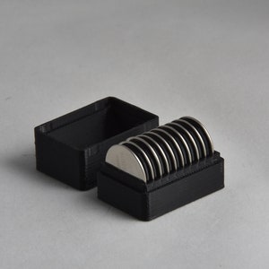 May include: A black plastic storage case with a lid, open to reveal a stack of silver button batteries.