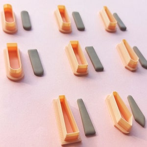 May include: Set of nine plastic cookie cutters in the shape of a coffin, with a matching fondant cutter for each. The cutters are a light orange colour and the fondant cutters are grey.