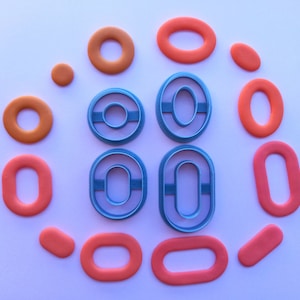 May include: A set of 10 cookie cutters in various sizes and shapes. The cutters are made of blue plastic and are shaped like circles, ovals, and doughnuts. The cutters are arranged in a circle on a white background.