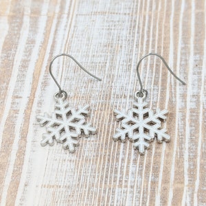 May include: A pair of silver snowflake dangle earrings. The earrings have a simple design and are perfect for adding a touch of winter charm to any outfit.
