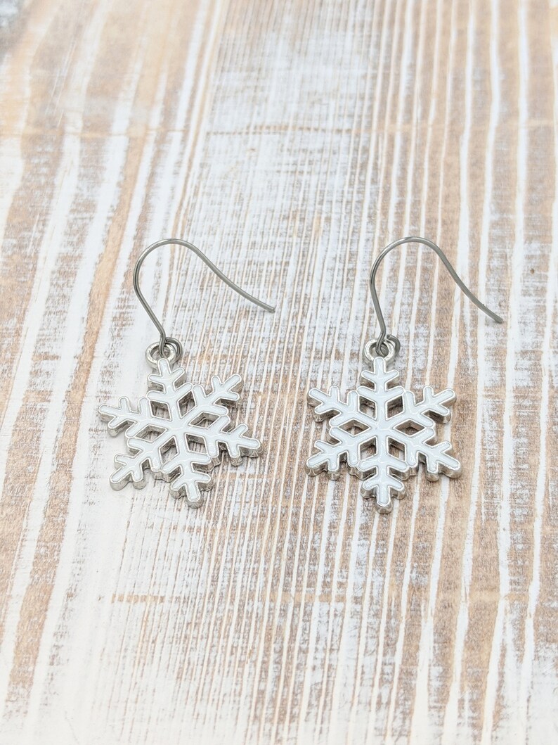 May include: A pair of silver snowflake dangle earrings. The earrings have a simple design and are perfect for adding a touch of winter charm to any outfit.