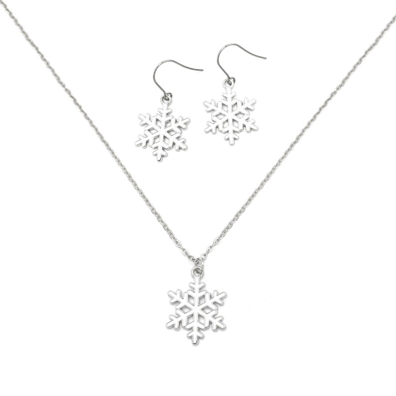 May include: A silver snowflake necklace and matching earrings set. The necklace has a delicate chain and a snowflake pendant. The earrings are dangle earrings with snowflake charms.