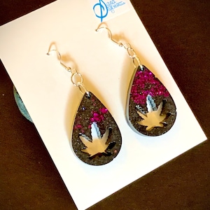 Svarta örhängen med punch-out-motiv och lila gnistrar