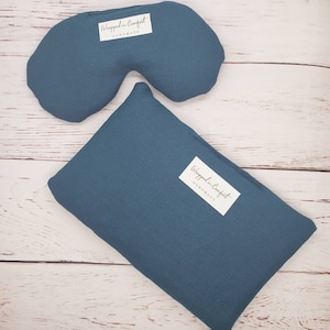 May include: Two teal blue fabric eye pillows with white labels that read "Wrapped in Comfort Handmade".