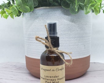 May include: A brown glass bottle with a black spray nozzle and a brown label that reads "Wrapped in Comfort Lavender Aromatherapy Heating Pad Mist 60 ml | 2 fl oz."