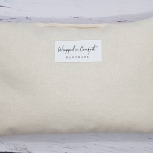 May include: A plain off-white pillow with a small white label that reads "Wrapped in Comfort HANDMADE".