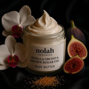May include: A jar of Nolah Organics Vanilla Orchid & Brown Sugar Fig Body Butter. The jar contains a creamy, off-white product. Orchids and sliced figs are arranged around the jar, with brown sugar crystals scattered around.