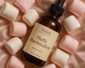 May include: A brown glass bottle with a dropper top, labeled "Nolah Organics Fluffy Marshmallow Body Oil 4 fl oz / 120 ml". The bottle is surrounded by white and pink marshmallows.