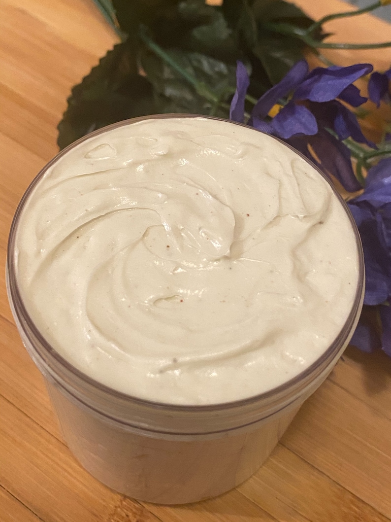 K&ouml;nnte beinhalten: Nahaufnahme einer wei&szlig;en, cremigen K&ouml;rperbutter in einem durchsichtigen Plastikbeh&auml;lter. Die Butter hat ein Spiralmuster und ist leicht strukturiert.