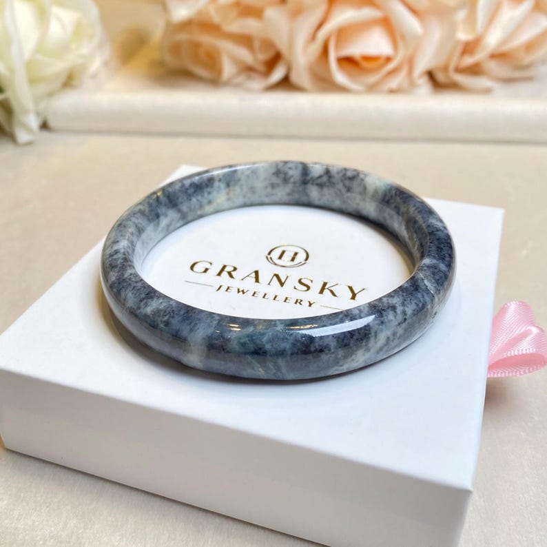 May include: A gray and white marble bangle bracelet with a polished finish. The bracelet is displayed in a white box with the text "Gransky Jewellery" printed on the box.