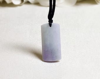 May include: A rectangular pendant necklace with a gradient of colors. The pendant transitions from a light lavender to a deeper purple at the base. It hangs from a black cord, showcasing a minimalist design.