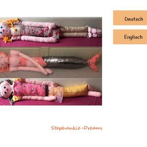 May include: Three handmade plush toys in the shape of a mermaid, a girl with a dress, and a girl with a rainbow shirt. The toys are all lying on a pink surface. The mermaid has a pink and orange tail with silver sequins. The girl with the dress has a pink and white dress with a floral pattern. The girl with the rainbow shirt has a pink and yellow shirt with a rainbow pattern.