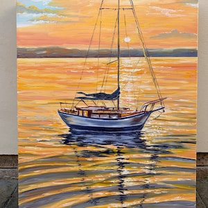 May include: A sailboat with white sails and a blue hull is anchored in a calm body of water. The sun is setting, casting a warm orange glow on the water and sky. The sailboat's reflection is visible in the water.
