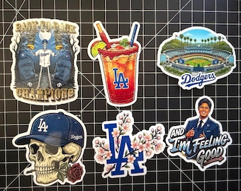 Könnte beinhalten: Eine Sammlung von Aufklebern mit Motiven der Los Angeles Dodgers. Designs umfassen einen Totenkopf mit einer Dodgers-Kappe und Rose, ein Stadion, einen Cocktail und Text mit der Aufschrift "Back to Back Champions" und "And I'm Feeling Good."