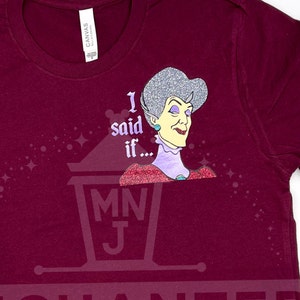 May include: A maroon t-shirt with a glittery image of a woman with the text "I said if..." and a small logo of a lantern with the letters "MNJ".