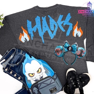 May include: A gray long-sleeved shirt with the word "Hades" in blue glitter on the back. The shirt is paired with a blue and black Hades-themed backpack, a pair of black shoes, and a pair of blue and black mouse ears with a skull and crossbones design.