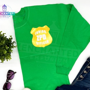 May include: Green long-sleeved shirt with a gold badge that says "Junior ZPD Officer".