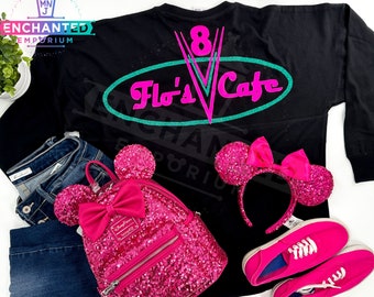 May include: Black long-sleeved shirt with a pink and teal "Flo's V Cafe" graphic. The shirt is paired with pink sequined Minnie Mouse ears, a pink sequined backpack, and pink trainers.
