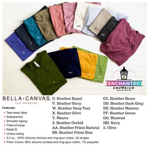 May include: A collection of folded Bella+Canvas t-shirts in various colors, including heather royal, navy, deep teal, olive, mauve, orchid, prism natural, prism blue, stone, dark gray, maroon, green, mustard, navy, and olive. The shirts feature a tear-away label, side seams, and shoulder taping.
