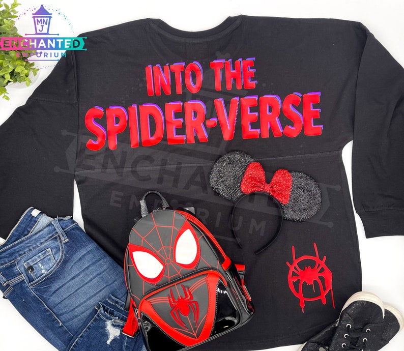 May include: Black long-sleeved shirt with the text "Into the Spider-Verse" in red and purple lettering. A black backpack with a red spider-man design, a black headband with red glitter mouse ears, and a red spider-man symbol are also pictured.