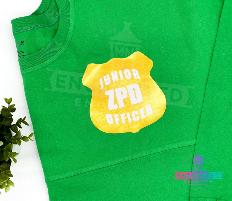 May include: A green t-shirt with a gold badge that says "Junior ZPD Officer" on it.
