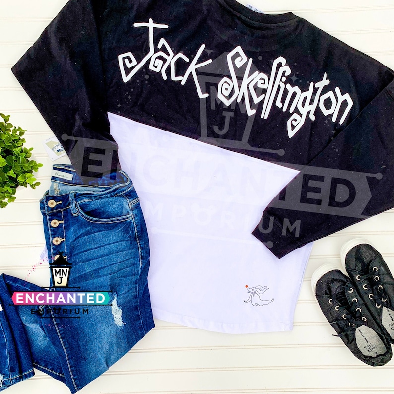 May include: A white and black long-sleeved shirt with the text "Jack Skellington" in white on the black portion of the shirt. The white portion of the shirt has a small embroidered image of Jack Skellington's ghost dog, Zero.