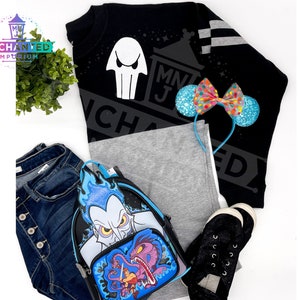 May include: Black sweatshirt with a white ghost graphic and the text "MNJ Enchanted" in white. A blue and pink bow headband, a pair of black sneakers, a pair of blue jeans, and a blue and black backpack with a Hades graphic.