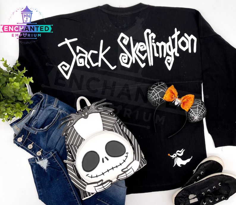 May include: Black long-sleeved shirt with "Jack Skellington" written in white on the back. A black and white striped backpack with a Jack Skellington face on the front. A black and white headband with a spiderweb design and an orange bow.