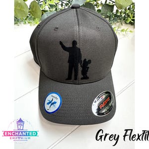 May include: A grey Flexfit baseball cap with a black silhouette of a man and a mouse on the front. The cap has a CoolDry logo on the side and a Flexfit logo on the back.